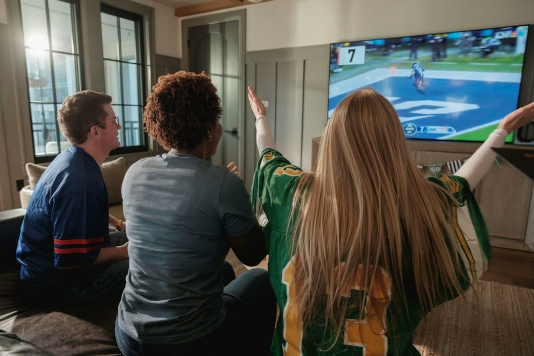 Vänner som tittar på en sportmatch på TV i vardagsrummet
